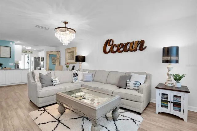 a living room with furniture kitchen view and a wooden floor