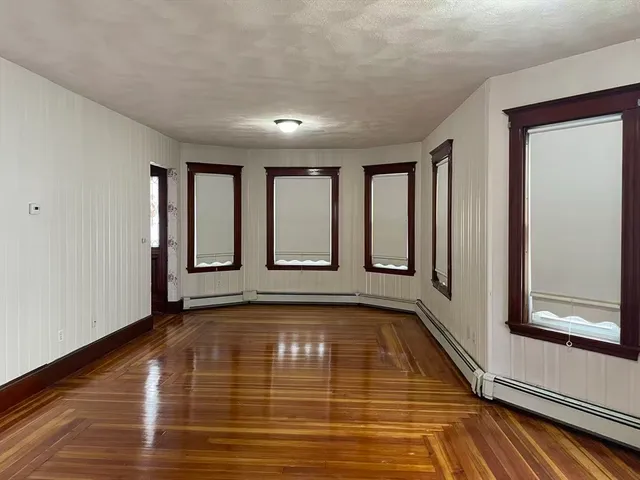 a view of an empty room with window and wooden floor