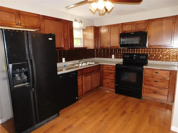 a kitchen with stainless steel appliances granite countertop a refrigerator a stove a sink and dishwasher with wooden cabinets