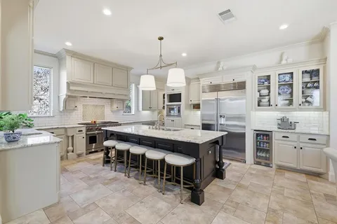 a large kitchen with kitchen island a stove a sink a oven and a dining table with cabinets
