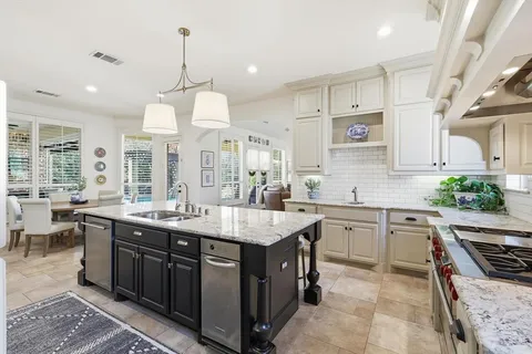 a kitchen with kitchen island granite countertop a sink a stove oven and white cabinets with wooden floor