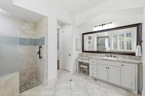 a bathroom with a granite countertop sink a mirror and a shower