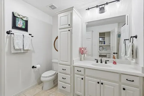 a bathroom with a toilet sink vanity granite and mirror