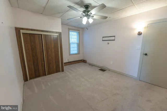 an empty room with windows and chandelier fan