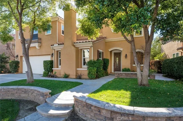 a view of a white house with a big yard plants and large trees