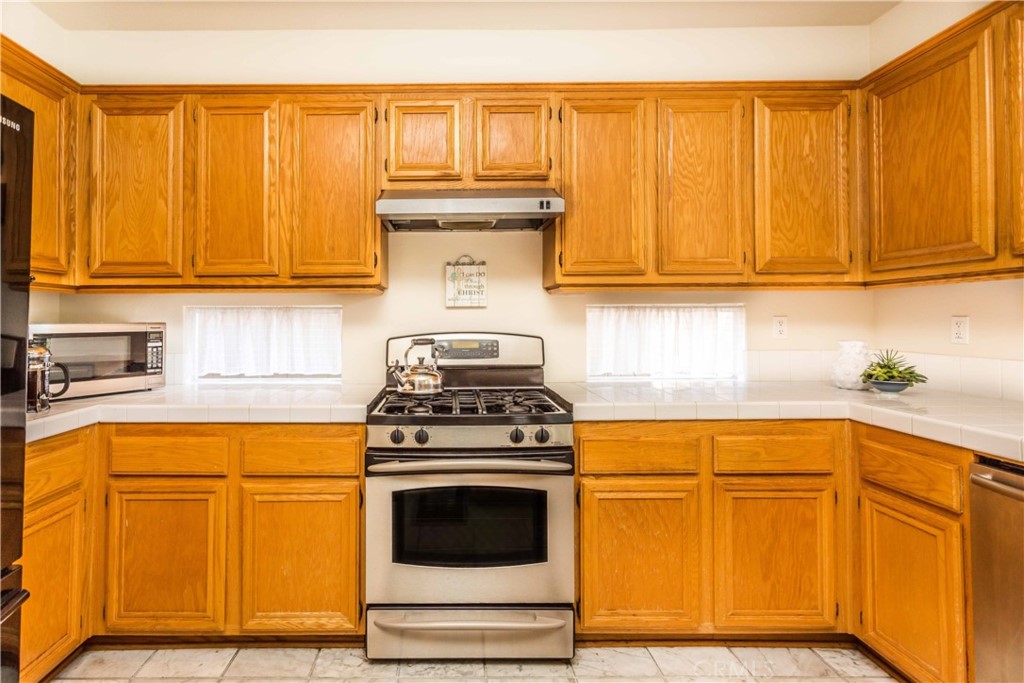 111 Colony Way Aliso Viejo, CA 92656 - Photo 12 of 29 a kitchen with granite countertop wooden cabinets and a stove top oven