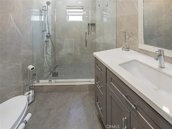 a bathroom with a granite countertop sink a toilet and shower