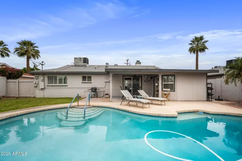 a view of a swimming pool with a bench and lawn chairs