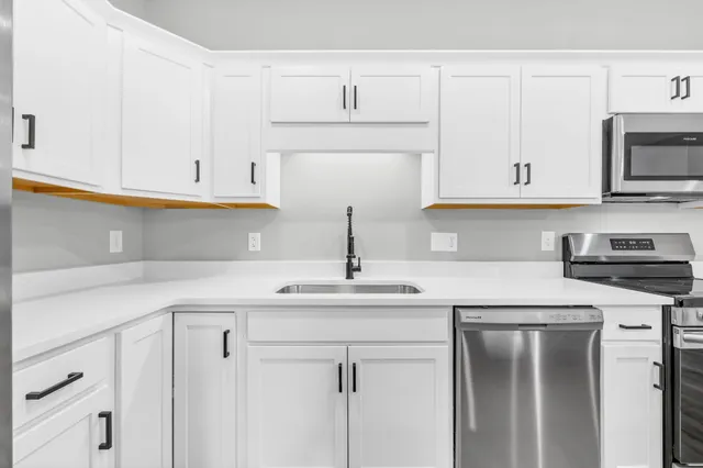a kitchen with white cabinets sink and stainless steel appliances