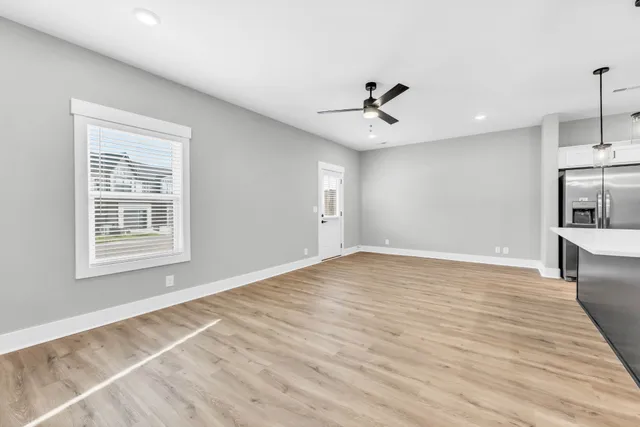 a view of empty room with wooden floor and ceiling fan