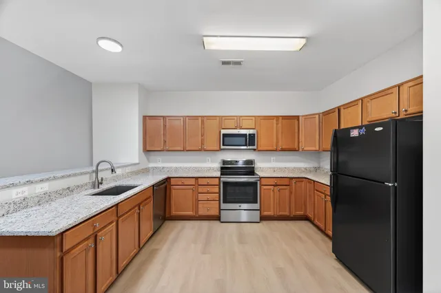 a kitchen with granite countertop cabinets stainless steel appliances a sink and a window