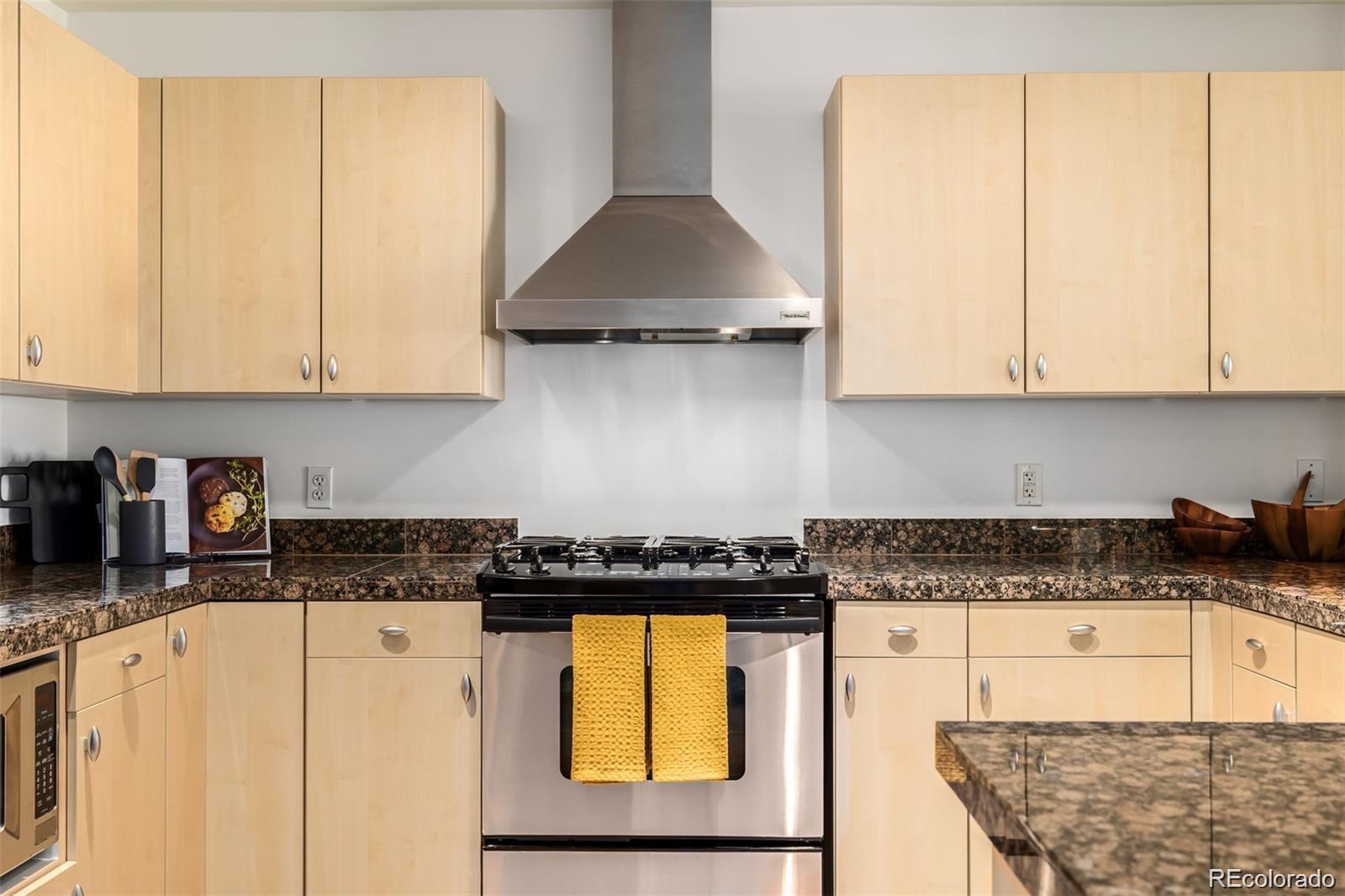 1560 Blake Street, Unit 810 Denver, CO 80202 - Photo 15 of 48 a kitchen with granite countertop a stove a sink a refrigerator and cabinets