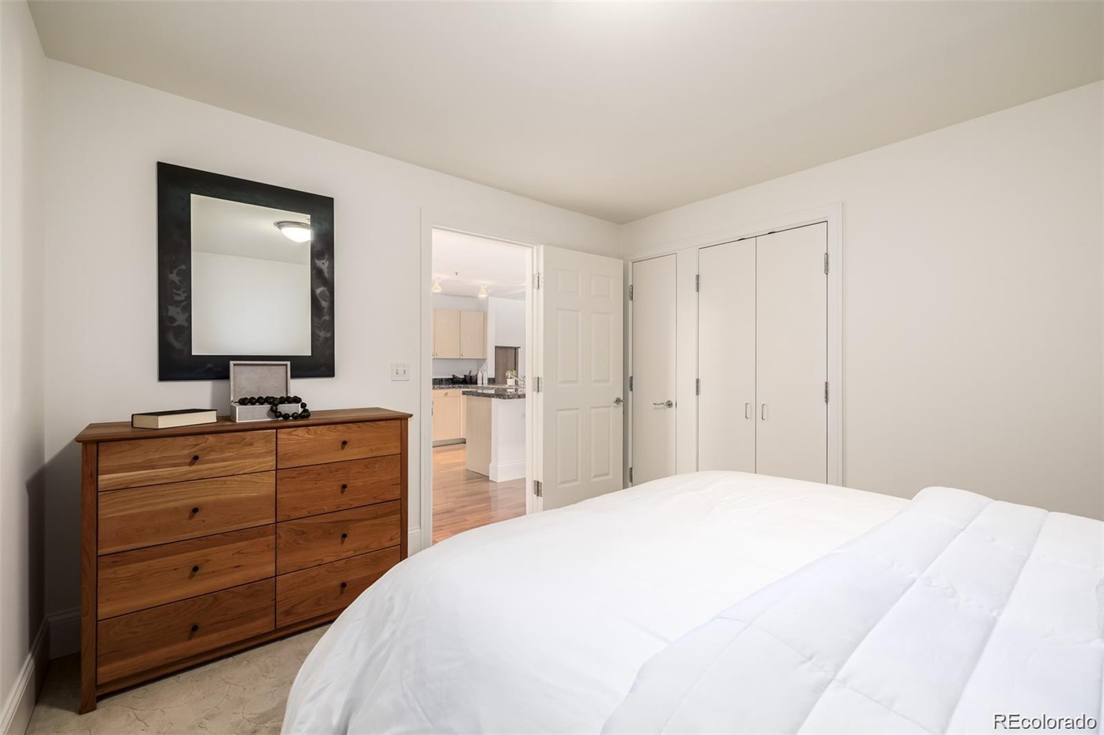 1560 Blake Street, Unit 810 Denver, CO 80202 - Photo 32 of 48 a spacious bedroom with a bed and a mirror on dresser