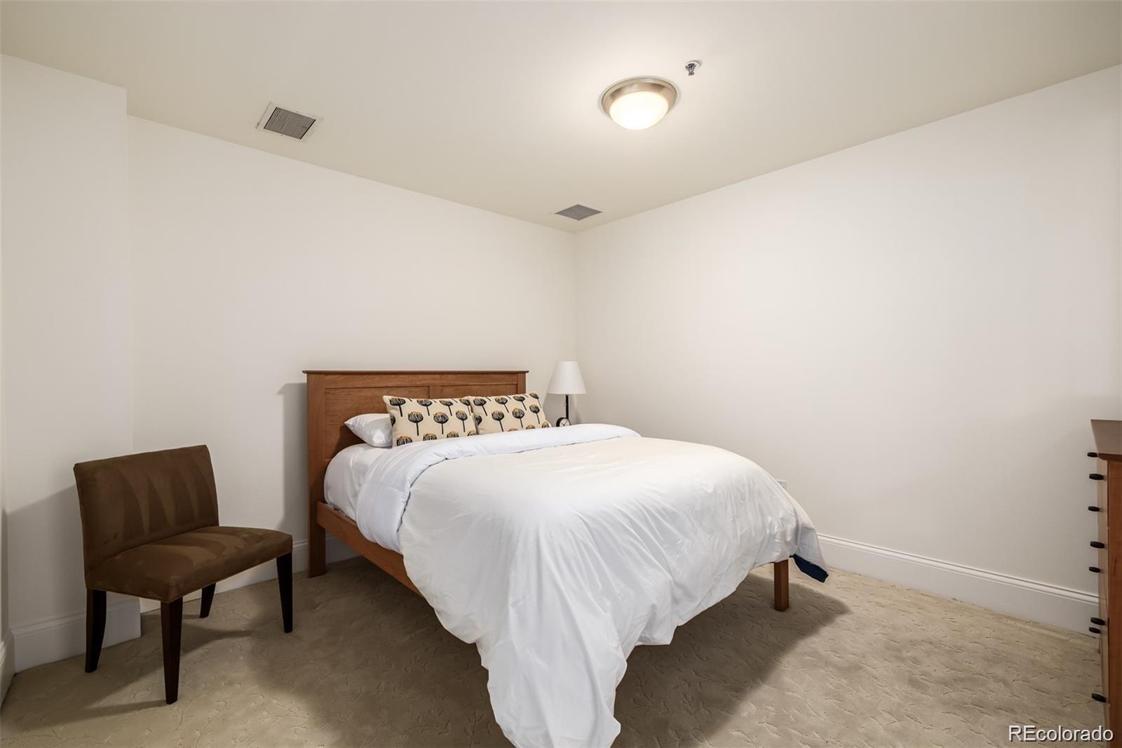 1560 Blake Street, Unit 810 Denver, CO 80202 - Photo 33 of 48 a bedroom with a bed and chair