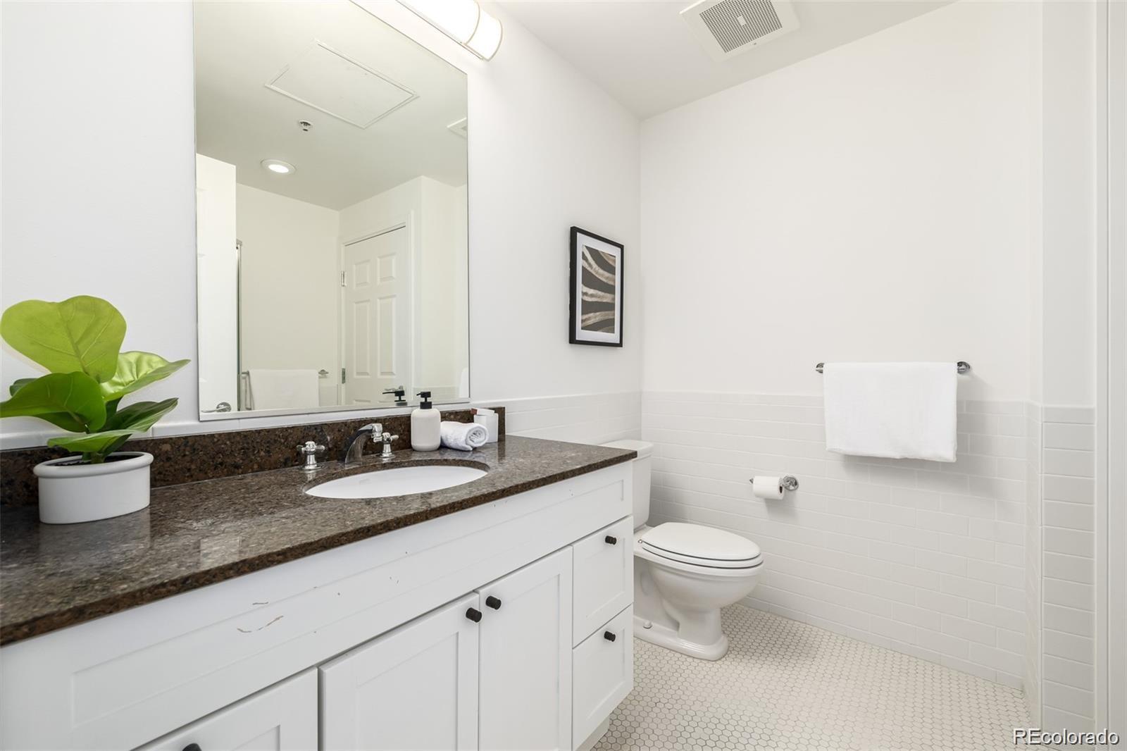 1560 Blake Street, Unit 810 Denver, CO 80202 - Photo 34 of 48 a bathroom with a granite countertop sink a toilet and a mirror