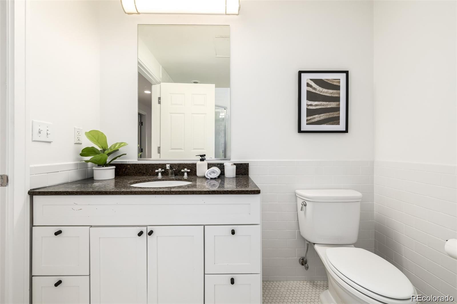1560 Blake Street, Unit 810 Denver, CO 80202 - Photo 35 of 48 a bathroom with a granite countertop toilet sink and mirror