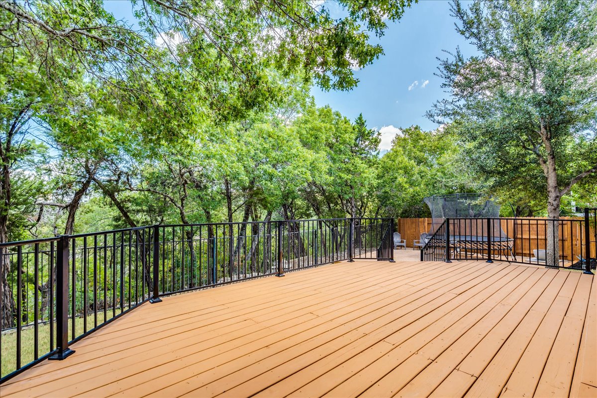 5009 Inks Clearing Lane Austin, TX 78738 - Photo 7 of 34 Mature trees frame a spacious wooden deck complete with secure railing.