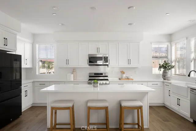 a kitchen with a sink a stove a refrigerator and white cabinets