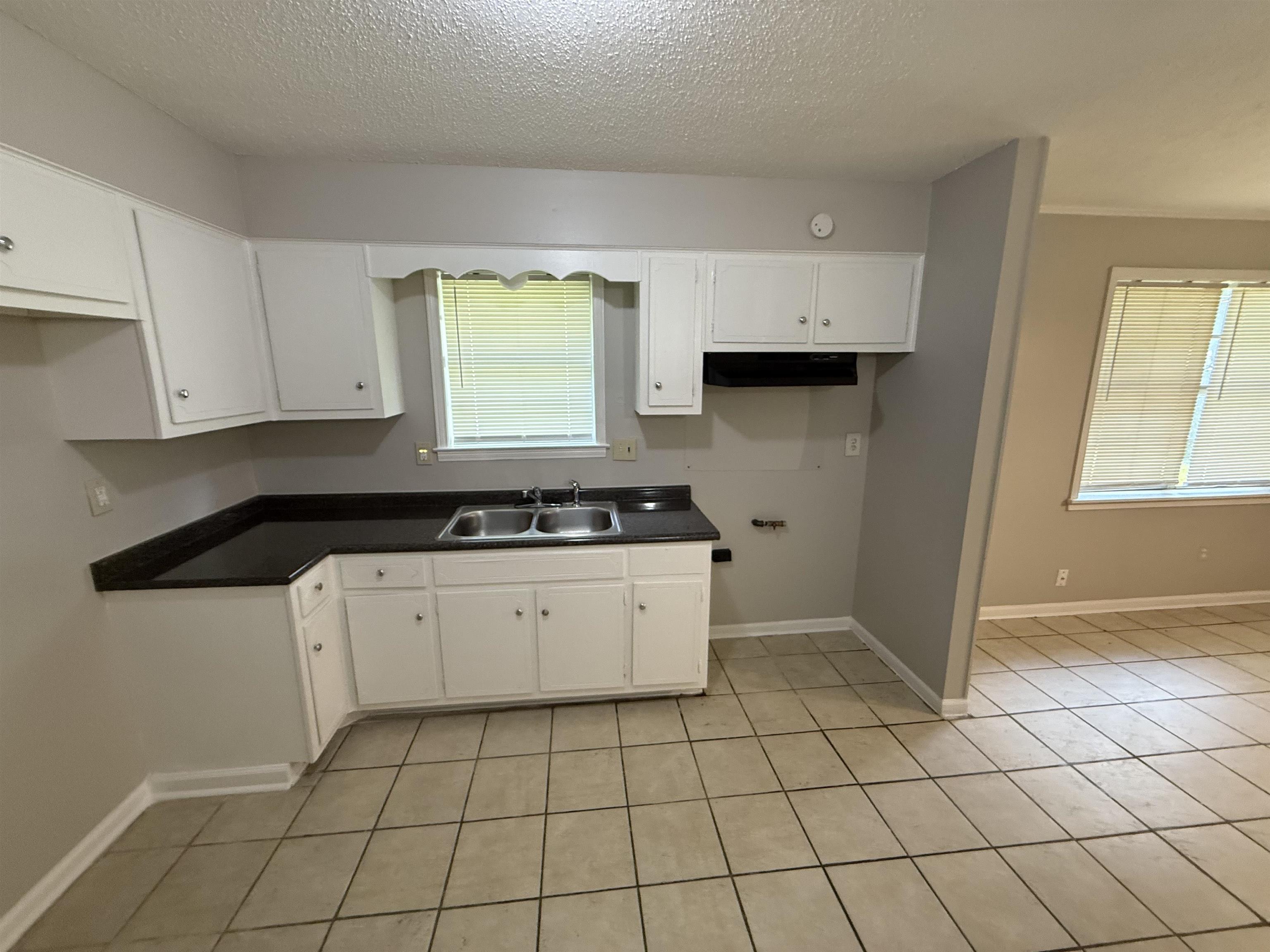 4213 Cochese Road Memphis, TN 38118 - Photo 2 of 11 Kitchen with white cabinets, light tile patterned flooring, dark countertops, a textured ceiling, and extractor fan