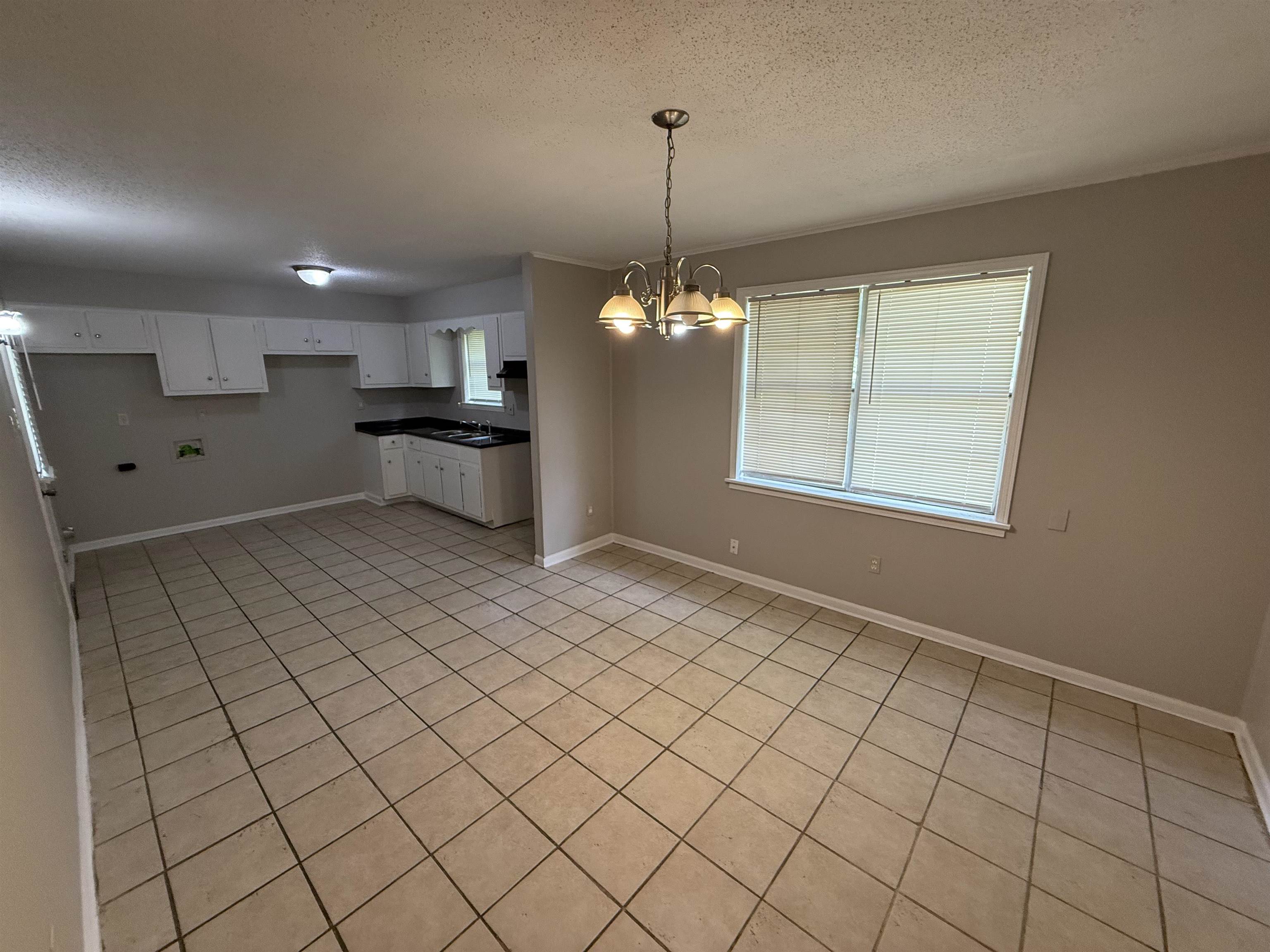 4213 Cochese Road Memphis, TN 38118 - Photo 4 of 11 Kitchen featuring a textured ceiling, a chandelier, light tile patterned floors, white cabinetry, and pendant lighting