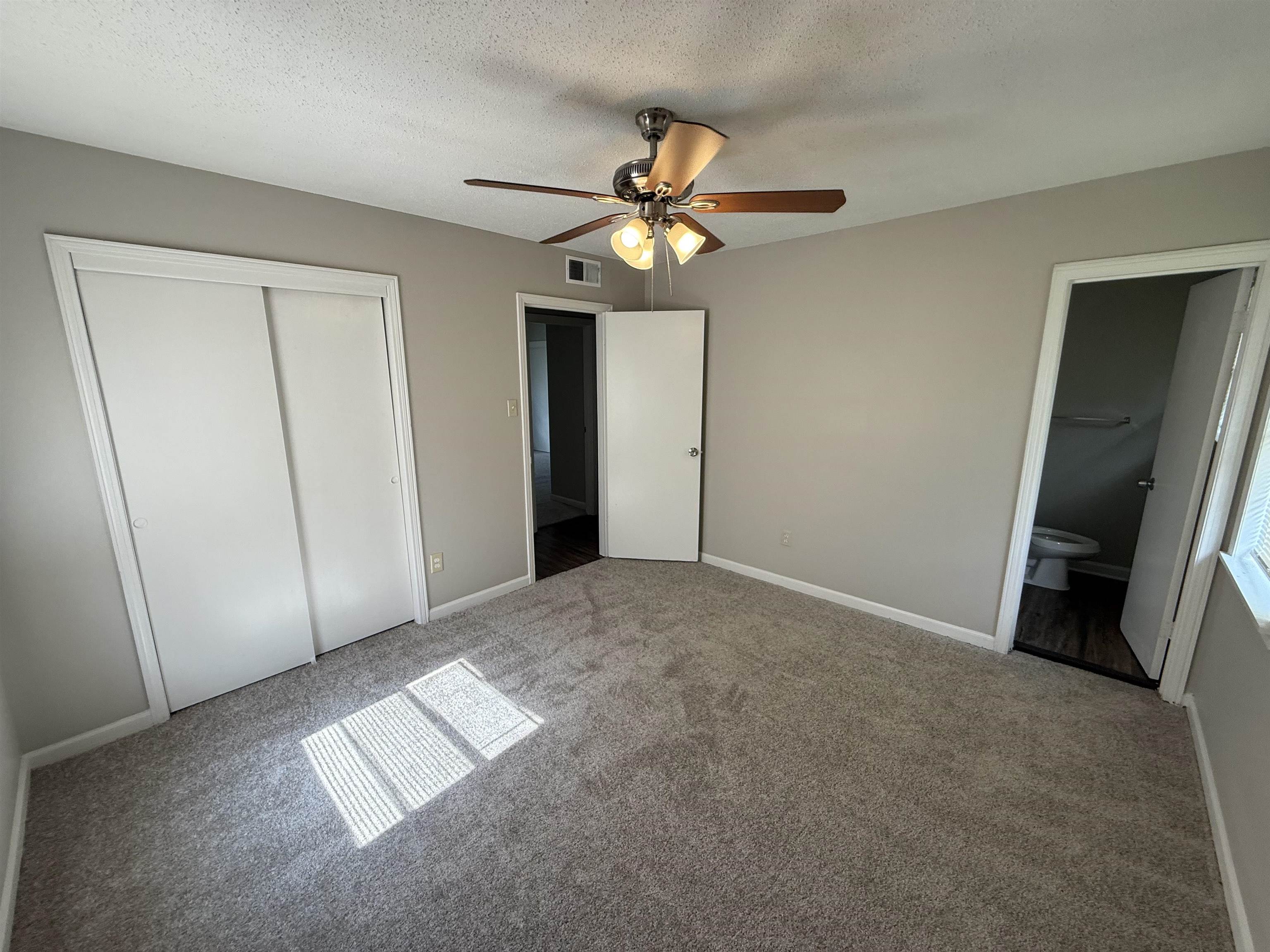4213 Cochese Road Memphis, TN 38118 - Photo 8 of 11 Unfurnished bedroom featuring carpet flooring, a closet, connected bathroom, a ceiling fan, and a textured ceiling