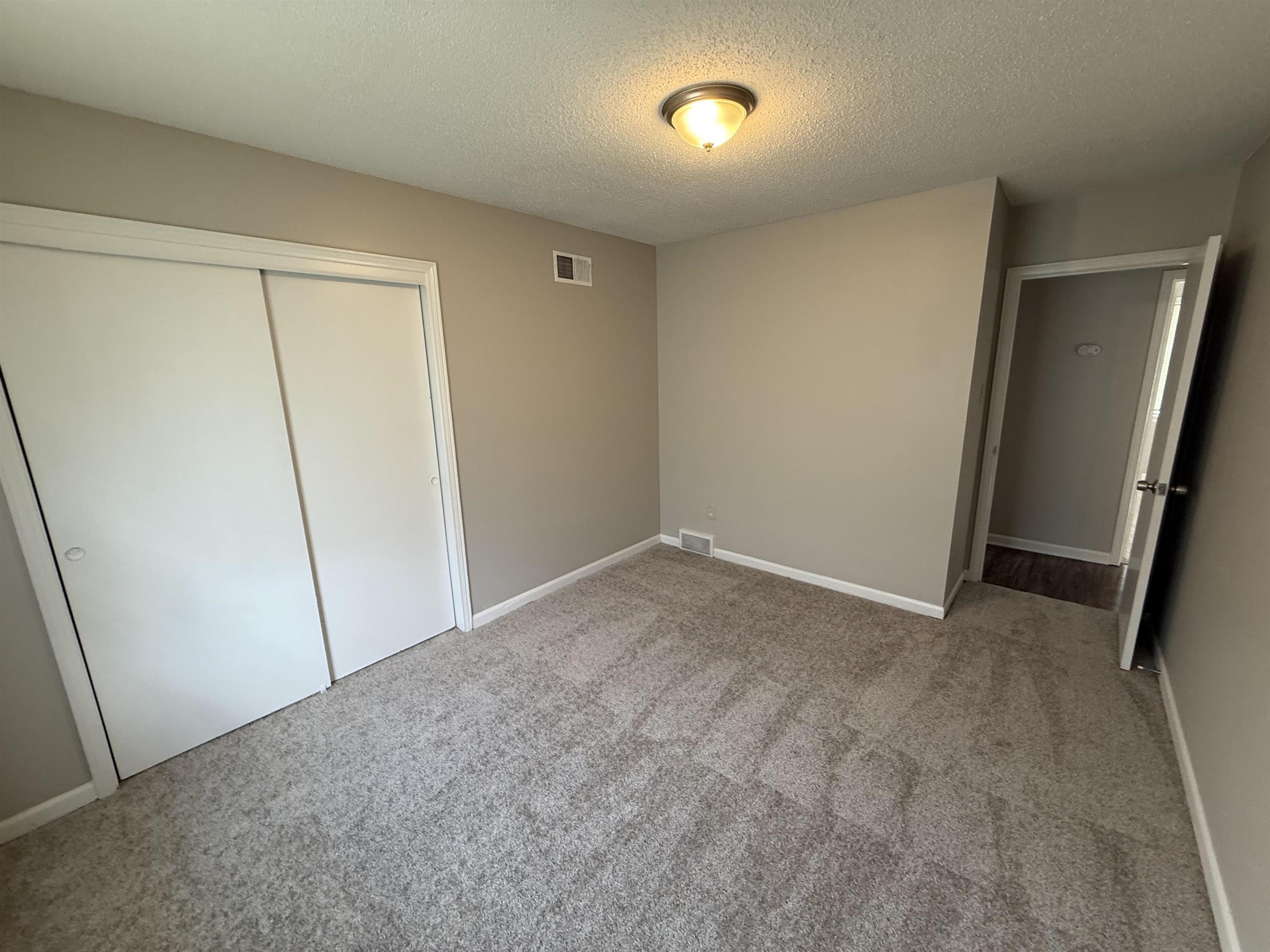 4213 Cochese Road Memphis, TN 38118 - Photo 9 of 11 Unfurnished bedroom featuring carpet flooring, a textured ceiling, and a closet
