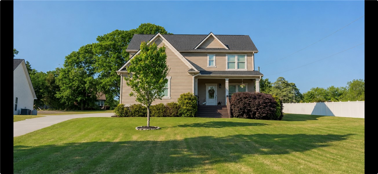 An inviting front porch leads into this charming two-story home with a manicured green lawn.