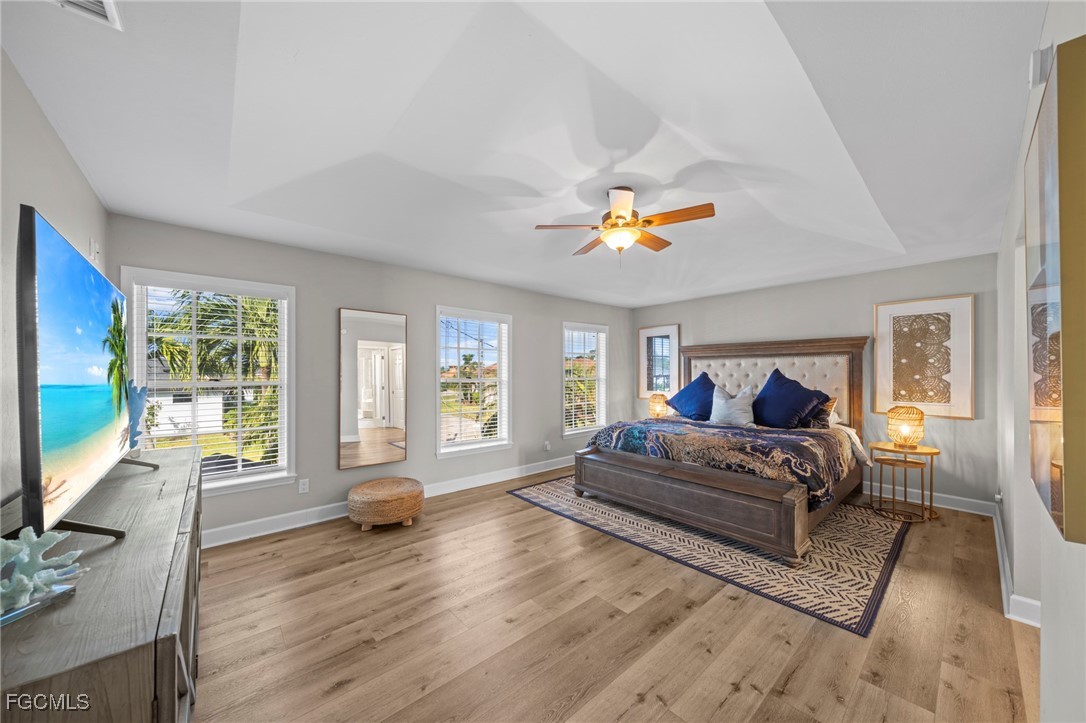 5303 Southwest 26th Court Cape Coral, FL 33914 - Photo 16 of 45 a bedroom with a large bed a flat tv screen and a chandelier