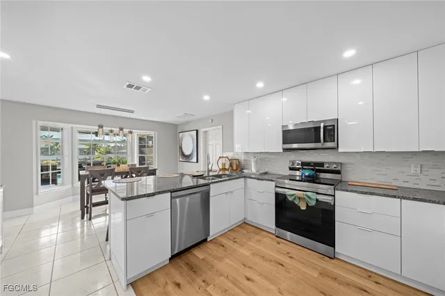 a kitchen with stainless steel appliances granite countertop a stove top oven a sink dishwasher a dining table and chairs with wooden floor