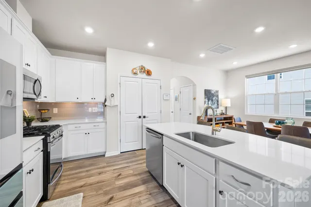 a kitchen with white cabinets a sink stove and refrigerator