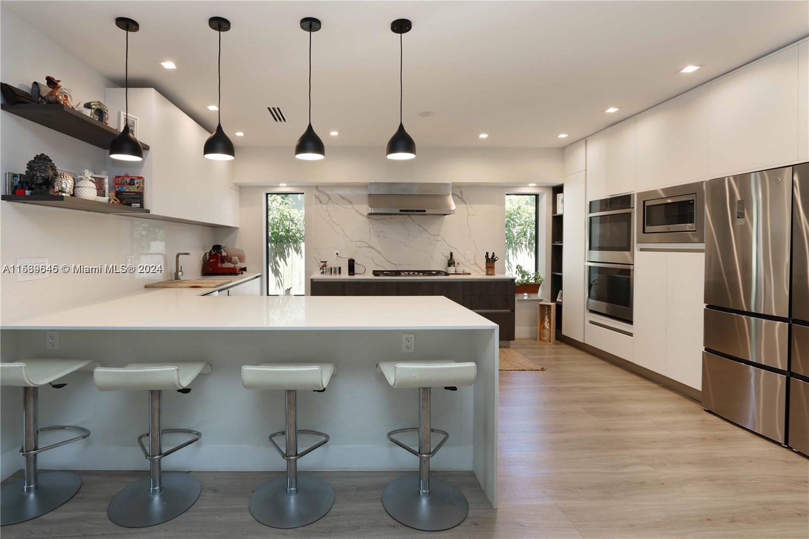 a kitchen with stainless steel appliances a stove a sink a refrigerator and chairs