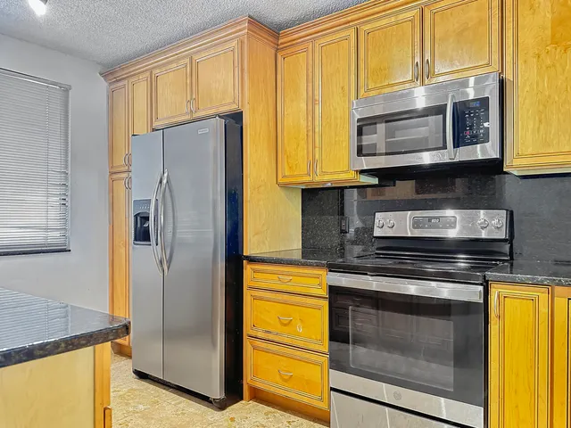 a kitchen with stainless steel appliances granite countertop cabinets and a refrigerator