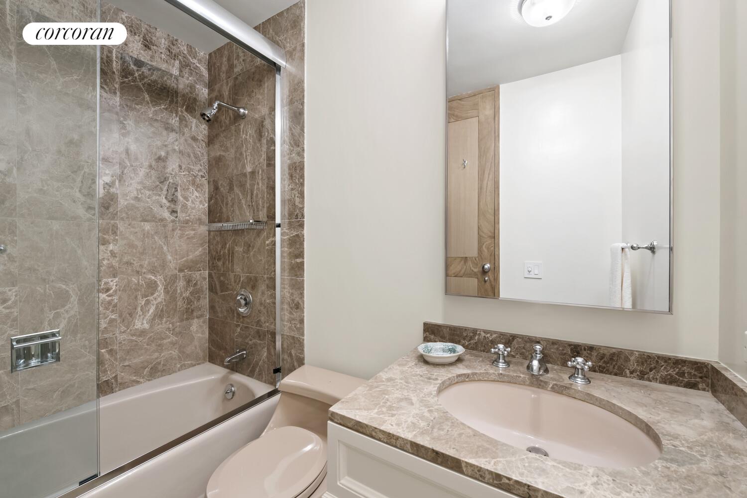 641 5th Avenue, Unit 28A Manhattan, NY 10022 - Photo 6 of 16 a bathroom with a granite countertop sink toilet and shower