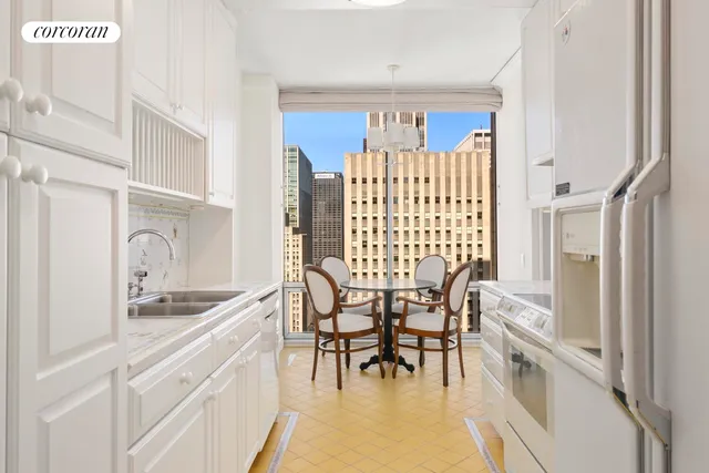 a kitchen with stainless steel appliances granite countertop a white table and chairs