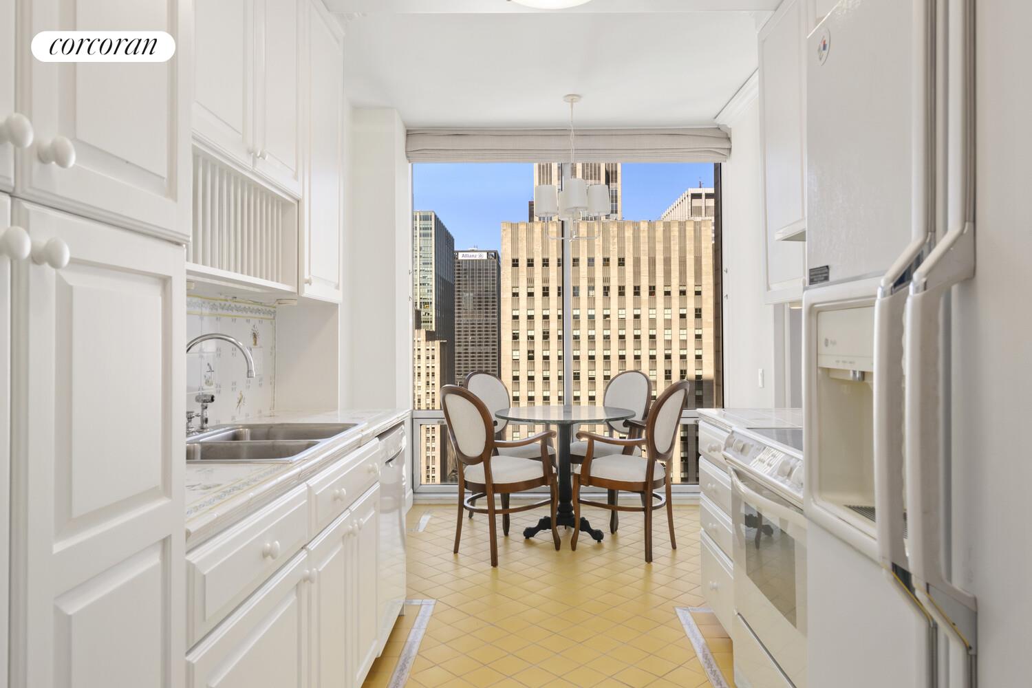 641 5th Avenue, Unit 28A Manhattan, NY 10022 - Photo 7 of 16 a kitchen with stainless steel appliances granite countertop a white table and chairs