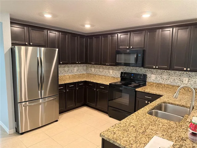 a kitchen with stainless steel appliances granite countertop a refrigerator stove and cabinets