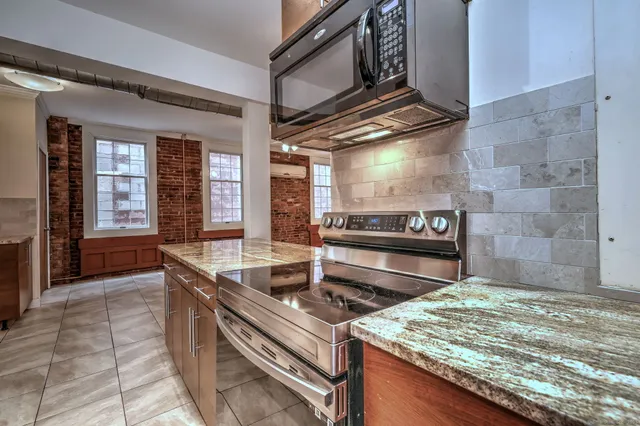 a kitchen with kitchen island granite countertop a stove and a sink