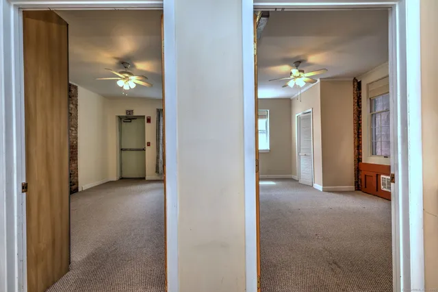 an empty room with windows closet and chandelier fan