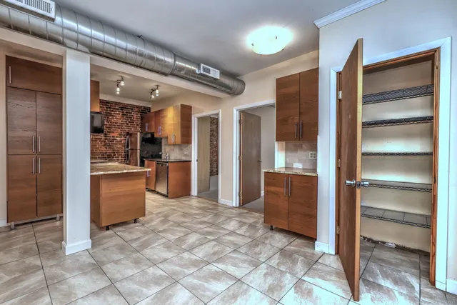 a kitchen with granite countertop a refrigerator and cabinets