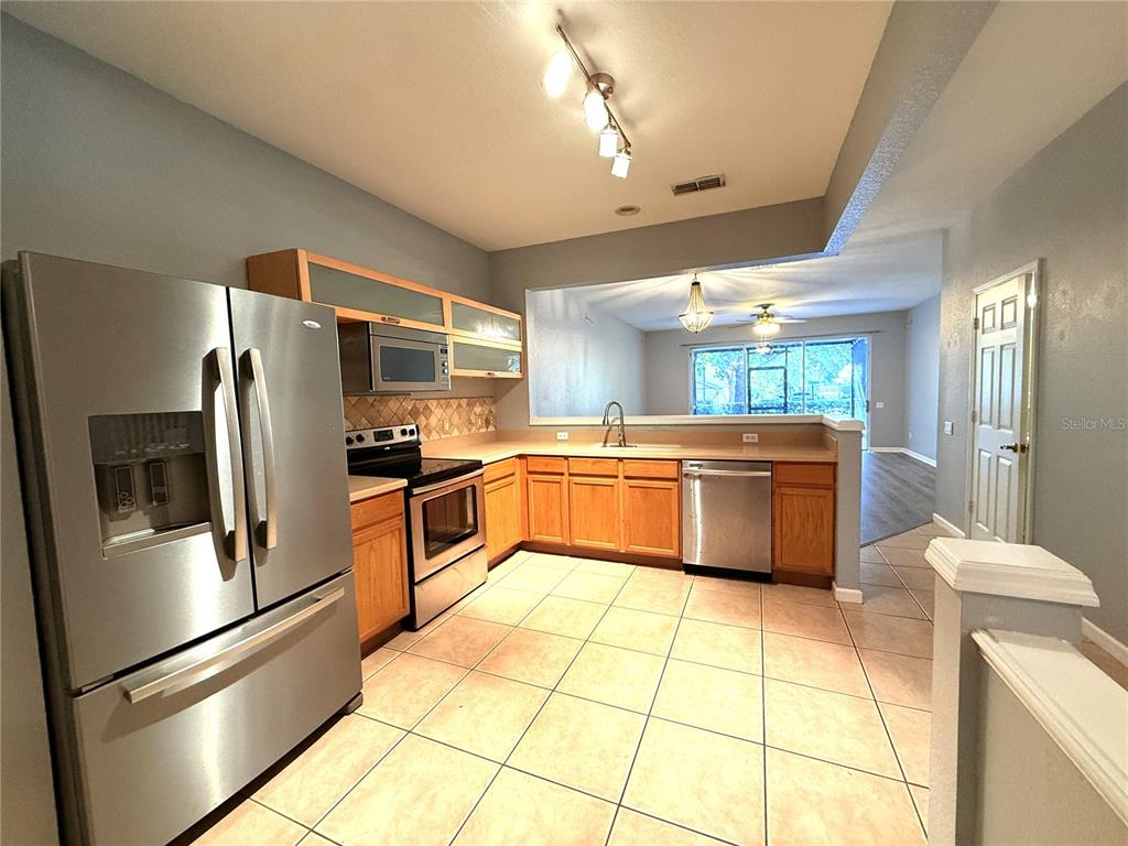 6360 Ranelagh Drive, Unit 104 Orlando, FL 32835 - Photo 7 of 18 a kitchen with stainless steel appliances a refrigerator sink and cabinets