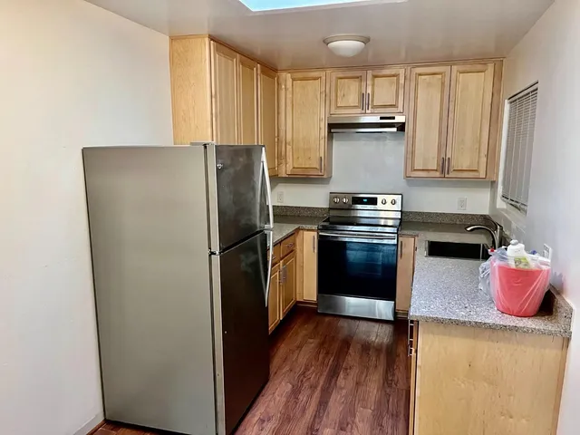 a kitchen with a refrigerator sink and wooden floor