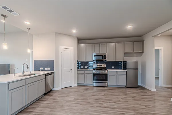 a kitchen with stainless steel appliances kitchen island hardwood floor sink and stove