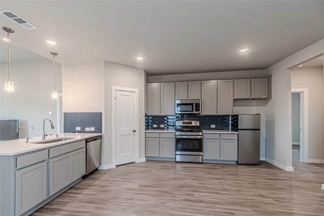 a kitchen with stainless steel appliances kitchen island hardwood floor sink and stove