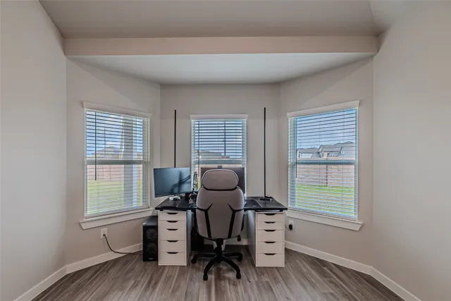an empty room with wooden floor ceiling fan and windows