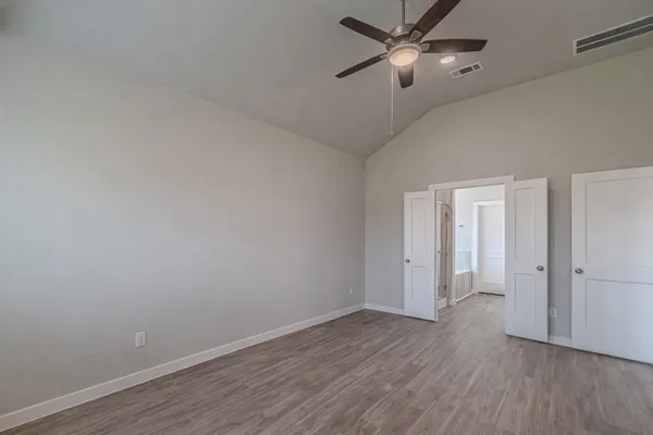 an empty room with wooden floor ceiling fan and windows