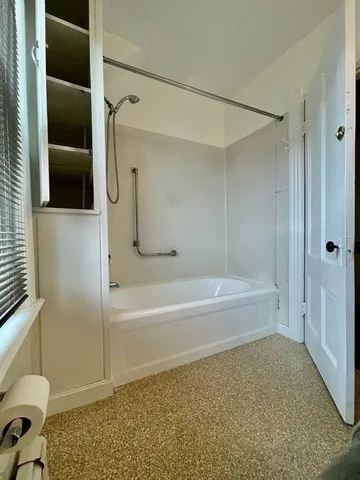 an empty room with wooden floor closet and windows