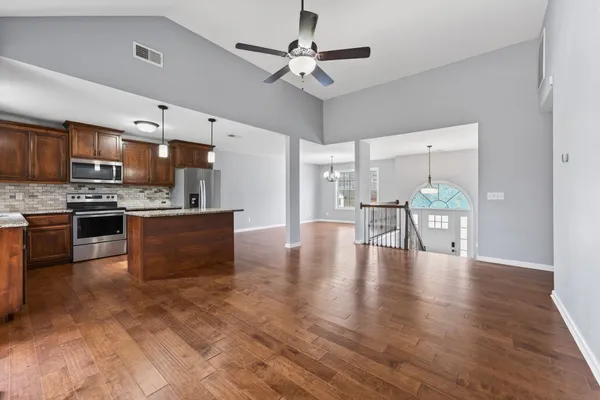 a kitchen with stainless steel appliances kitchen island granite countertop a stove a refrigerator a microwave oven with a dining table and chairs