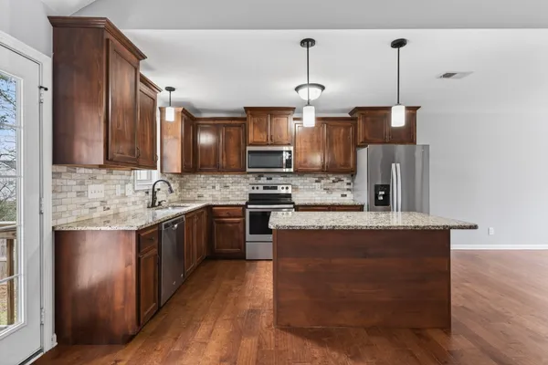a large kitchen with stainless steel appliances granite countertop a sink stove and refrigerator