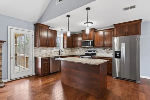 a kitchen with stainless steel appliances granite countertop a refrigerator a sink and a stove