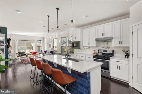 a kitchen with stainless steel appliances kitchen island granite countertop a table chairs stove and white cabinets